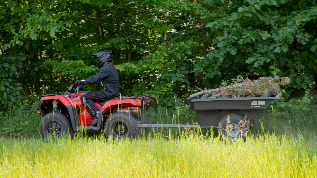 A rider hauling some hay on the back of a Honda Rancher