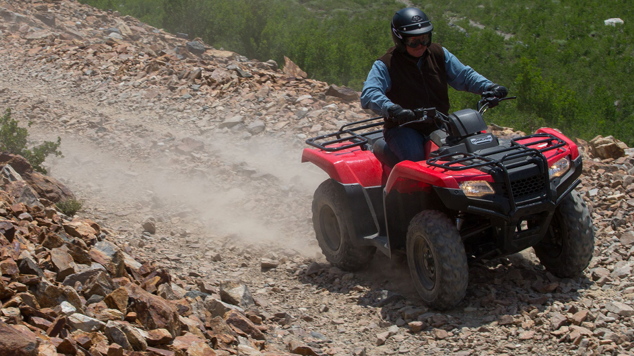 A rider n a Honda Rancher on a rocky trail 