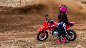 A rider on a Honda Trail motorcycle on a dirt track