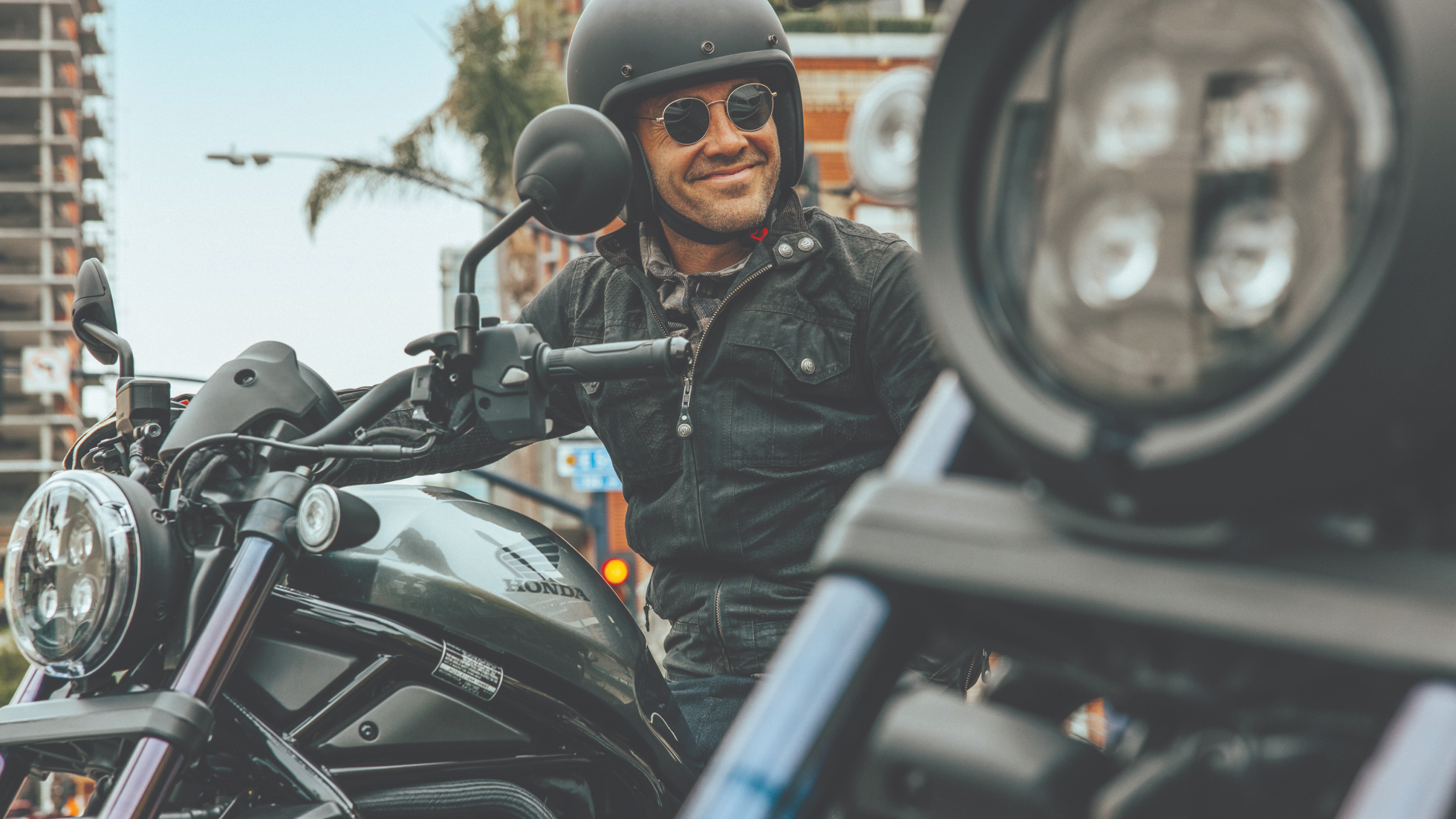 A rider wearing a black helmet smiling on a Honda Rebel