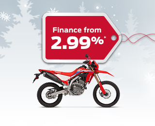 A Honda CRF300L on a winter backgroud with snowflakes with a red gift tag advertising a 2.99% interest rate 